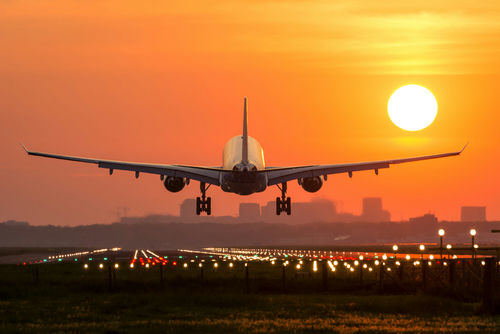 shutterstock_419990866.jpg Airplane landing at sunset on illuminated runway.