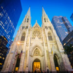 Bishop’s Shocking Freemason Claim ROCKS THE CHURCH… Gothic cathedral illuminated at dusk surrounded by modern skyscrapers