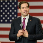 Evangelical KINGMAKERS Tip Scales: Rubio Surges! A politician speaking into a microphone in front of an American flag