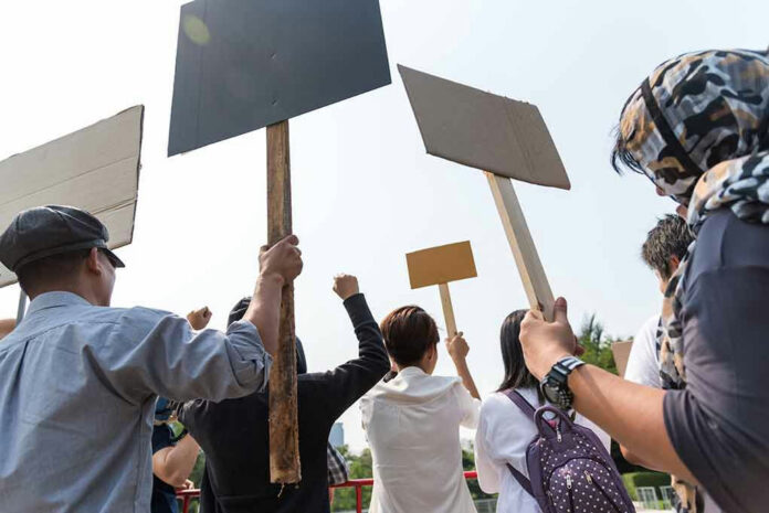 People holding blank protest signs outdoors.