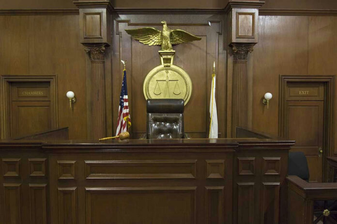 121502698 Judges bench in an empty courtroom, scales emblem above.