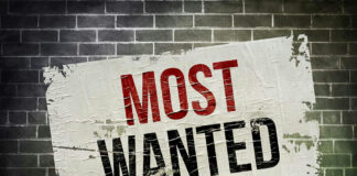 Most Wanted poster on brick wall.