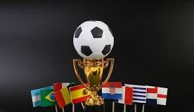 A golden soccer trophy with a black and white ball on top, surrounded by small flags of various countries