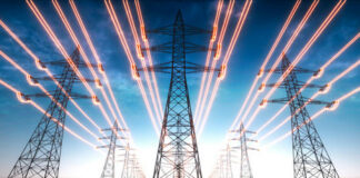 High-voltage transmission towers with glowing power lines at dusk
