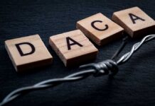 DACA Bombshell at the White House Wood letter tiles spelling DACA beside barbed wire on dark surface