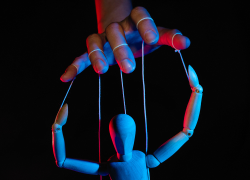Concept,Of,Control.,Marionette,In,Human,Hand.,Objects,Are,Colored A hand controlling a wooden puppet with strings against a dark background