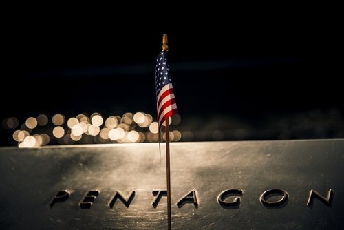 Close-up,Of,An,American,Flag,Draped,Across,The,Iconic,Pentagon Close-up of a small American flag on a reflective surface with the word PENTAGON in the background