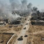 ISIS No. 2 Down—What’s MISSING? Aerial view of a war-torn city with smoke rising from buildings