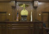 Judges bench in an empty courtroom, scales emblem above.
