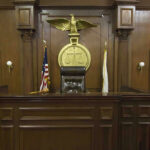 British Columbia’s Lawsuit Could Redefine AI Accountability Judges bench in an empty courtroom, scales emblem above.