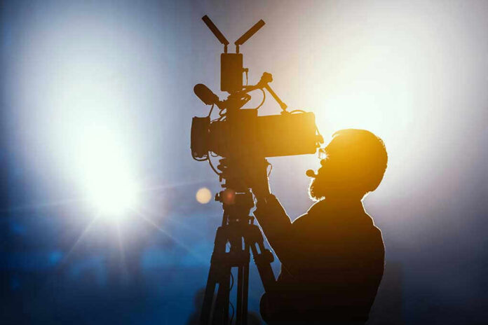 1297145938 Cameraman silhouetted against bright studio lights.