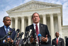 Men in suits speaking at podium outside courthouse.