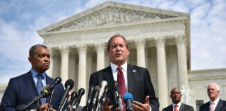 Men in suits speaking at podium outside courthouse.