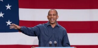 Speaker at podium in front of large American flag