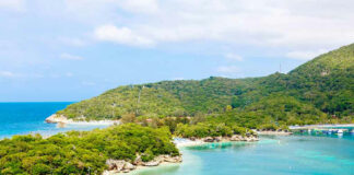 Tropical island with turquoise water and lush green hills.