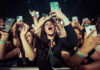 Concert crowd cheering and taking photos with phones.