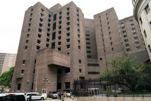 shutterstock1478945648-2jpg Tall concrete building with numerous windows and adjacent parked cars.