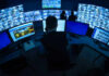 Surveillance control room with multiple monitors and operators.