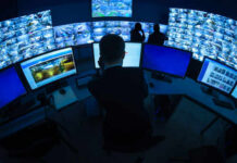 Surveillance control room with multiple monitors and operators.