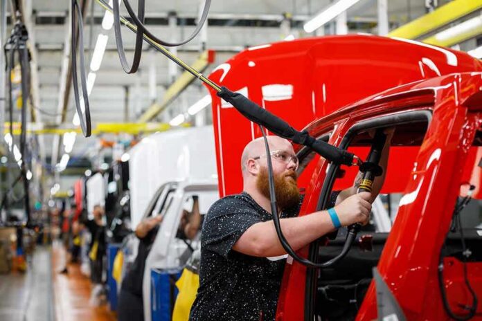 shutterstock_1158833029 Worker assembles red vehicle on factory line