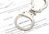 Handcuffs on an arrest warrant document