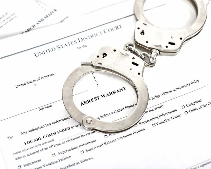 District,Court,Arrest,Warrant,Court,Papers,With,Handcuffs,Isolated,On Handcuffs on an arrest warrant document