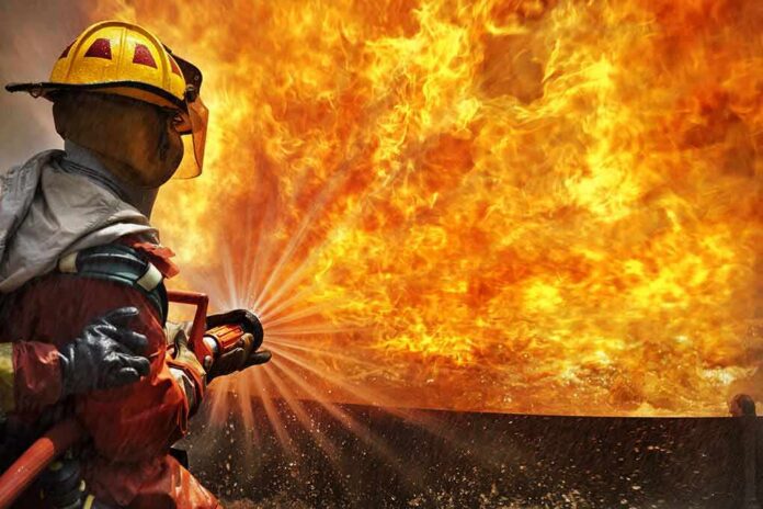 Firefighter spraying water at a large blaze