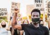 Protester wearing mask raises fist during demonstration