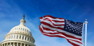 U.S. Capitol building with waving American flag.