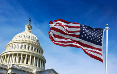 shutterstock_1915477927 U.S. Capitol building with waving American flag.