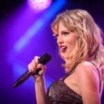 Lockdown Fuels: No Phones, No Photos, No Proof? Singer performing on stage with a microphone under colorful lights