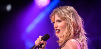 Singer performing on stage with a microphone under colorful lights