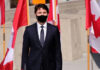 A man in a suit with Canadian flags in background.