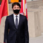 A man in a suit with Canadian flags in background.