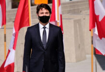 Canada’s Fighter Choice Could Reshape Jobs, Technology, and Defense A man in a suit with Canadian flags in background.