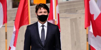A man in a suit with Canadian flags in background.