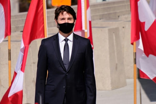 shutterstock_2040965933 A man in a suit with Canadian flags in background.