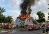 A house engulfed in flames with firefighters responding