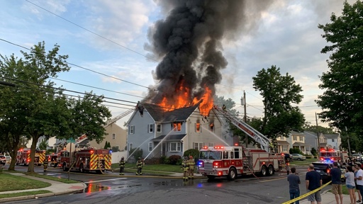 A house engulfed in flames with firefighters responding