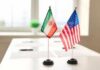 American Freed by Iran, but Was It Goodwill or Another Prisoner Bargain? Mini flags of Iran and the United States on a conference table