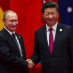 The Alliance Is Spending More Than Ever Vladimir Putin and Xi Jinping shaking hands at event.