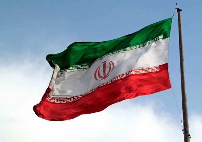 Iranian flag flying against a clear sky.