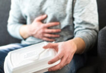 Person holding stomach with one hand, food container in other.