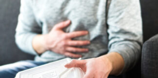 Person holding stomach with one hand, food container in other.