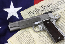 Gun on U.S. Constitution with American flag background.