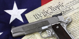 Gun on U.S. Constitution with American flag background.