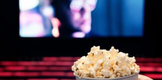 Person holding popcorn in empty movie theater.