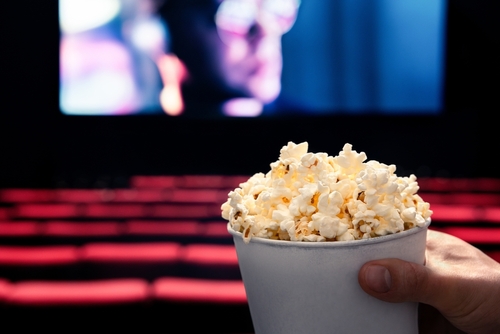 Person holding popcorn in empty movie theater.