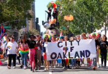 Group marching in Oakland pride parade with banner.