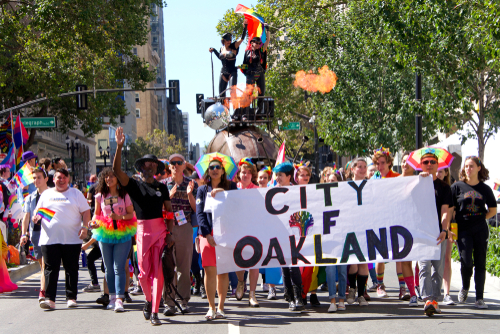 Group marching in Oakland pride parade with banner.